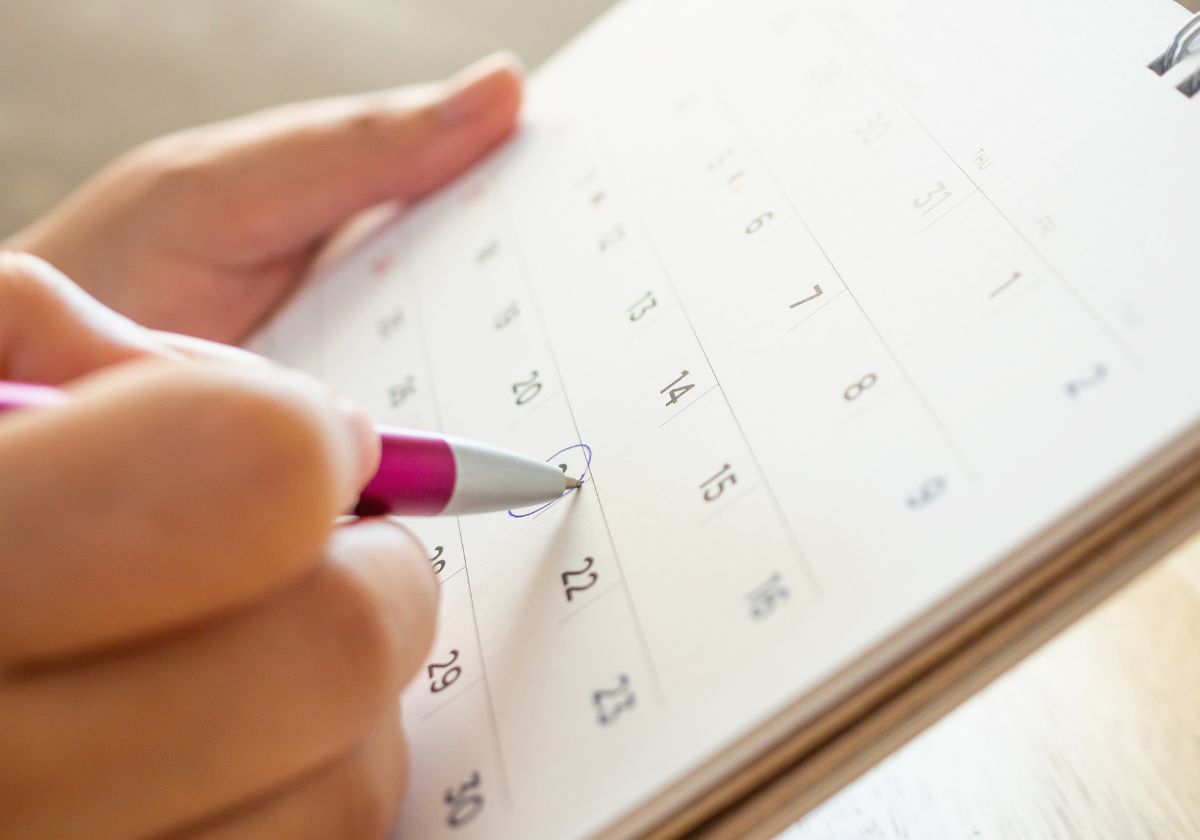 Pessoa escrevendo em calendário mensal.
