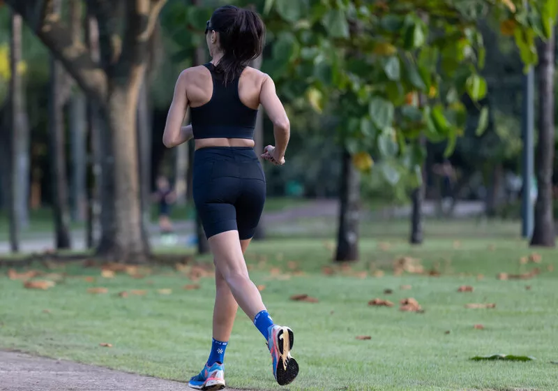 Mulher correndo em parque com roupas de treino