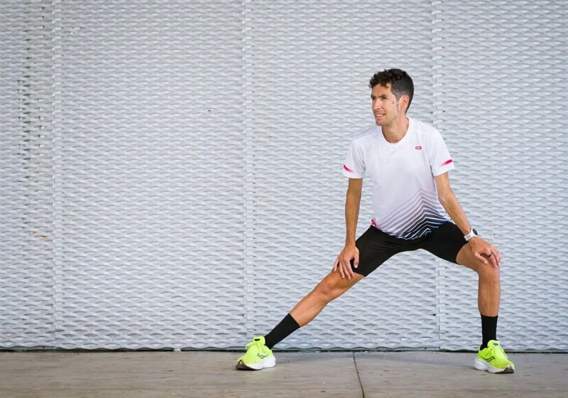 Homem realizando alongamento em pista esportiva