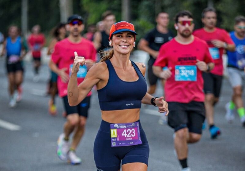 Corredora sorridente em evento esportivo de rua.