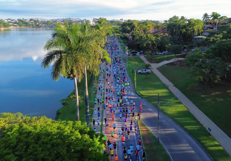 Pessoas correndo em evento ao ar livre próximo a lagoa